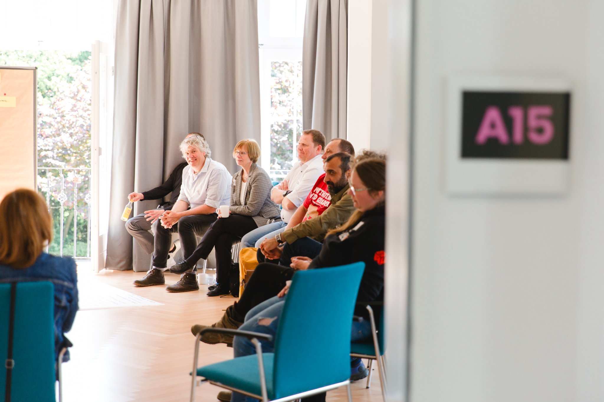 Personen sitzen in einem Raum bei einer Gesprächsrunde