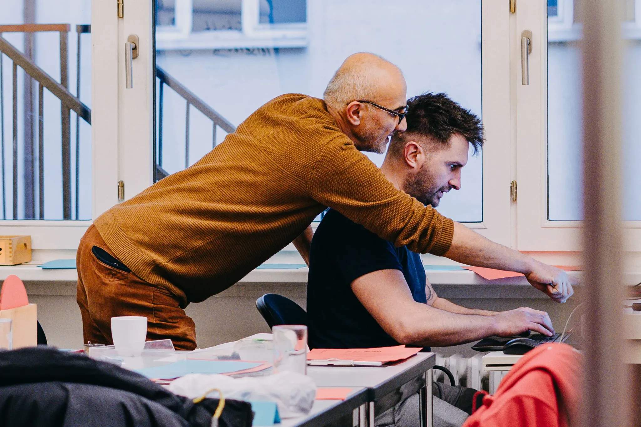 Eine Person erklärt einer anderen Person etwas an einem Computer.